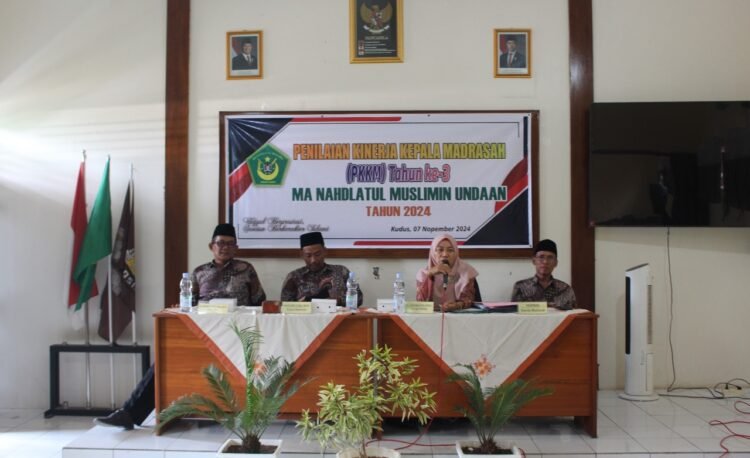 Penilaian Kinerja Kepala Madrasah (PPKM)Kudus, 09 November 2024 – Penilaian Kinerja Kepala Madrasah (PPKM) di Madrasah Aliyah (MA) Nahdlatul Muslimin Undaan tahun 2024 telah dilaksanakan dengan sukses pada Sabtu, 08 November 2024. Kegiatan ini berlangsung secara tatap muka di Ruang Multimedia dan dihadiri oleh berbagai pihak terkait.  Acara dibuka dengan sambutan dari Pengawas Madrasah Aliyah (MA) Nahdlatul Muslimin, Ibu Hj. Chasnah, S.Pd., M.Pd.I. Dalam pidatonya, beliau menyampaikan bahwa PPKM merupakan bagian integral dari penjaminan mutu pendidikan yang wajib dilakukan oleh setiap lembaga pendidikan. “PPKM adalah alat penting untuk melakukan evaluasi diri serta merancang perbaikan ke depan demi meningkatkan kualitas pendidikan di madrasah,” ujar Ibu Chasnah. Beliau juga menekankan pentingnya kontrak belajar di kelas serta motivasi bagi para guru untuk mengikuti lomba dan kompetisi guna mengasah keterampilan profesional mereka. “Selain mendukung prestasi siswa, guru juga harus terus berinovasi dan berkompetisi untuk memajukan diri,” tambahnya.  Setelah sambutan pembukaan, acara dilanjutkan dengan pemaparan oleh Kepala MA Nahdlatul Muslimin Undaan, Muhlisin, S.Ag., M.Pd. Dalam kesempatan ini, beliau mengungkapkan berbagai rencana pengembangan madrasah, program unggulan, serta inovasi-inovasi yang akan datang. “Kami di MA Nahdlatul Muslimin selalu berkomitmen untuk memperbaiki dan mengembangkan kualitas sumber daya manusia di seluruh civitas akademika. Berbagai program unggulan dan inovasi yang kami rencanakan bertujuan untuk membawa madrasah ini menuju tingkat yang lebih baik,” jelas Muhlisin.  Kegiatan PPKM ini diharapkan dapat memberikan masukan berharga yang dapat mendorong peningkatan kualitas pendidikan di MA Nahdlatul Muslimin Undaan, serta menjadikan madrasah ini lebih berdaya saing dan berprestasi di masa depan. di MA Nahdlatul Muslimin Undaan Berjalan Sukses